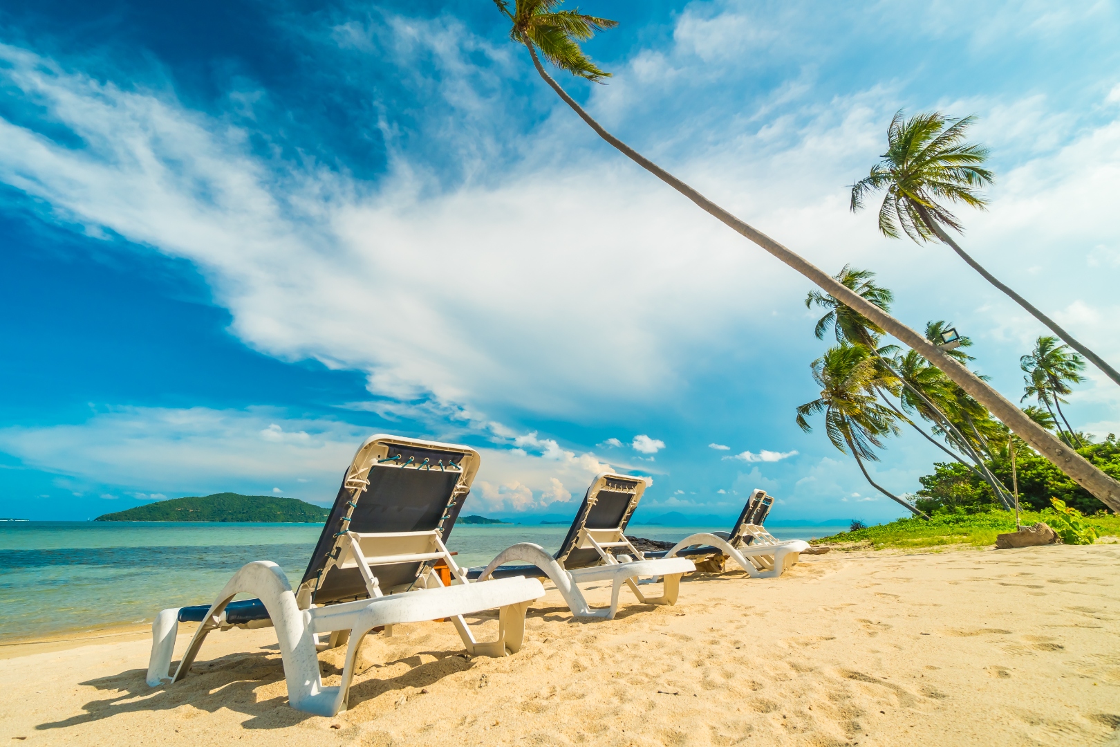 Tropical beach with sun loungers and palm trees, Phuket golf holiday Thailand