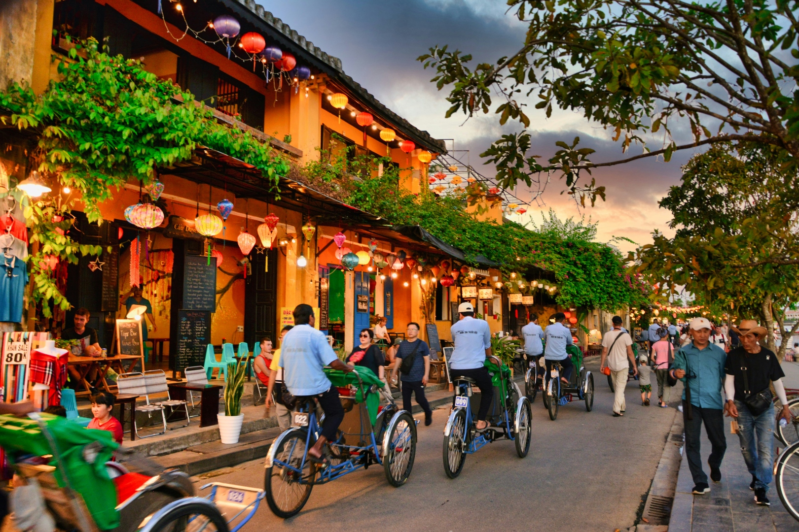 Cyclos and tourists on Hoi An ancient town street at dusk — cultural golf holidays Vietnam